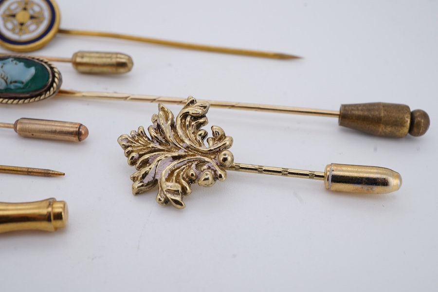 A collection of six stick pins, comprising: three gold stick pins, one set with a hardstone cameo, Austrian assay marks; a gold stick pin with a faceted edge; and a gold stick pin of Masonic design, stamped 9CT, combined